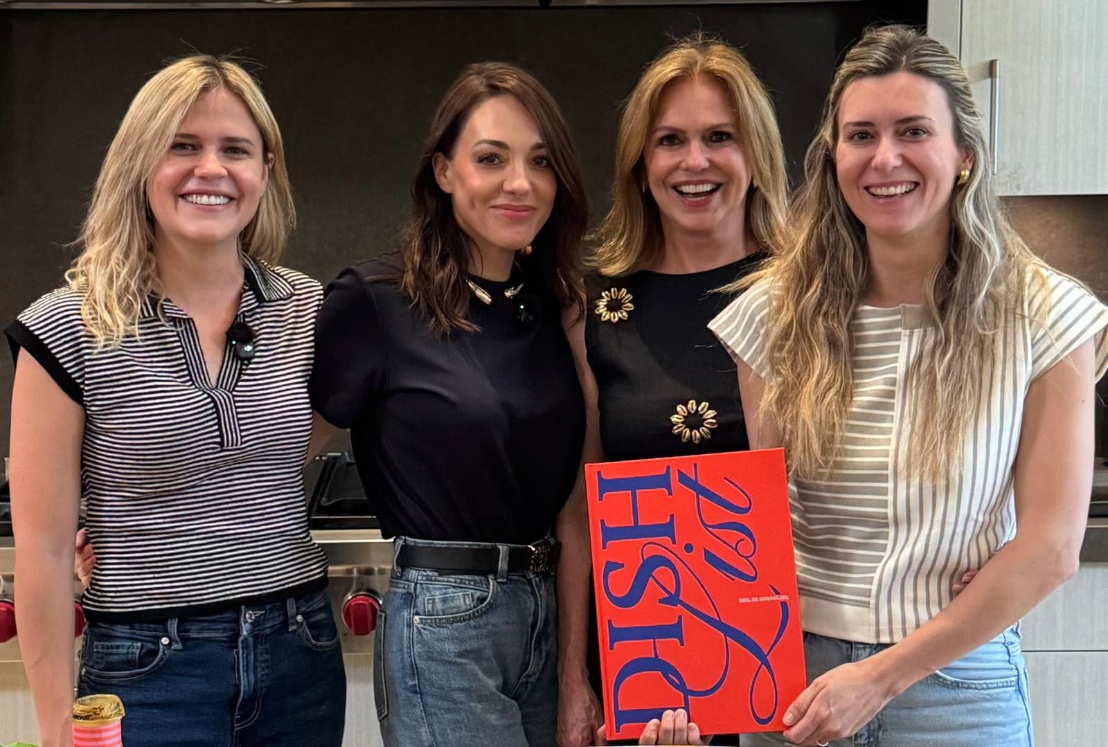 Las creadoras de Dish List en la cocina, sonriendo, una sosteniendo el libro impreso.