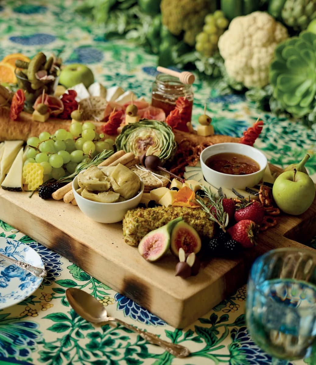 Tabla editorial de quesos, frutas e higos sobre un mantel estampado.